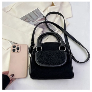 Detail view of black plush flap handbag with silver hardware and phone for scale
