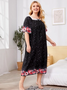 Detail of square neckline with white lace trim and bow on black floral sleepwear