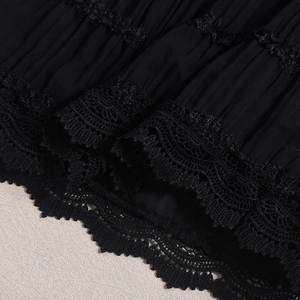 Close-up of black lace cutout ruffles and pleated fabric texture on a sexy skirt