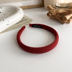 Detailed close-up of a handmade red sponge headband with a black woven logo tag