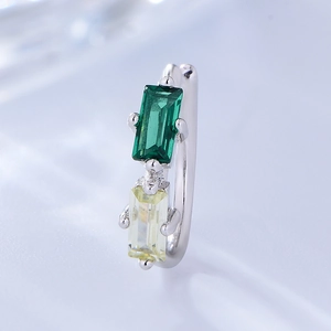 Macro detail of S925 silver ear cuff featuring emerald green and champagne square zircons