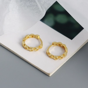 Detailed close-up of gold geometric chain link earrings on a vintage book page