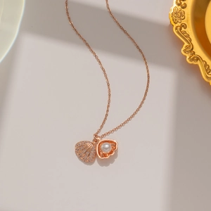 Detailed close-up of rose gold fan-shaped shell pendant with pearls and pavé zircons