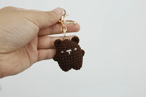 Close-up of a handmade brown knitted bear keychain with golden metal ring detail