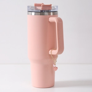 Detail of a matte pink tumbler featuring a gold chain with letter A heart pendant