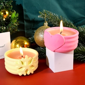 Dettaglio di candele natalizie in contenitori a cuore e fiocco di neve per decorazione