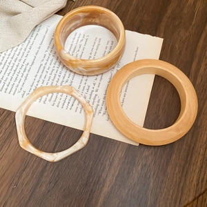 Three-piece set of retro resin bangles with wood and tortoiseshell textures on book
