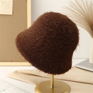 Close-up of thick dark brown plush bucket hat on a gold stand with warm winter decor