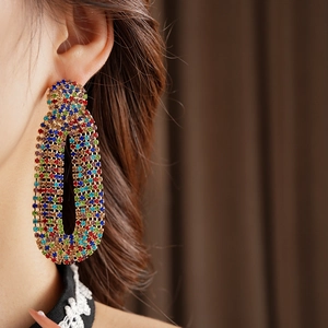 Close-up of vintage gold oval earrings with colorful rhinestones on female model