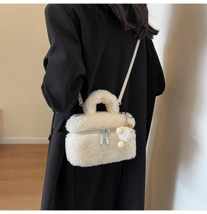White faux fur crossbody bag with matching plush charm worn by model in casual style