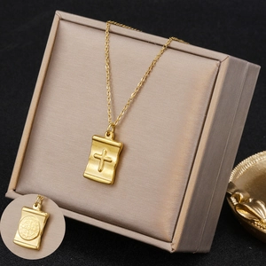 Elegant gold scroll necklace with embossed cross pendant on a beige jewelry display box
