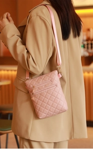 Detail of pink quilted crossbody phone bag with gold zippers and adjustable strap