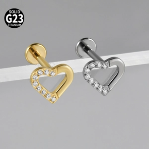 Macro detail of G23 titanium heart labret stud with white zircon inlay in gold and silver