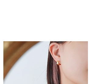Close-up of polished gold hoop earrings worn on ear showing elegant french minimalist style