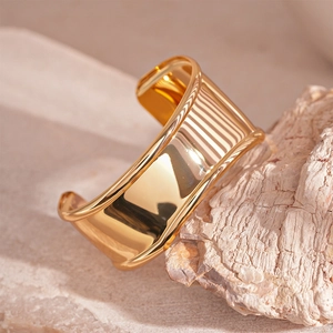 Macro view of wide gold-plated cuff bracelet with polished finish on natural stone
