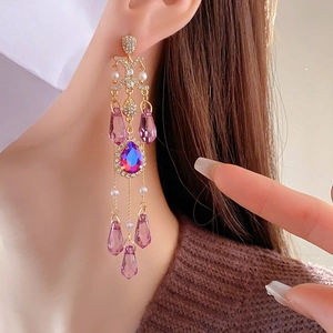 Model wearing gold tassel earrings with purple crystals and pearls in an elegant side profile
