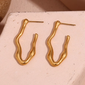 Detailed view of wavy V-shaped 18K gold plated earrings on a pink stone background