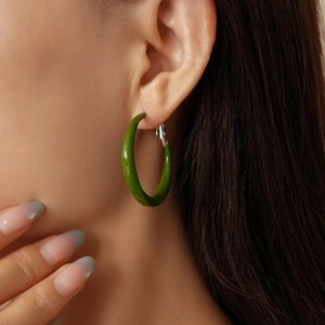 Primo piano di orecchini a cerchio in resina verde su modella con finitura lucida