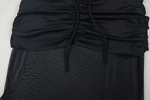 Close-up of ruched black fabric detailing and sheer mesh stitching on sexy backless dress