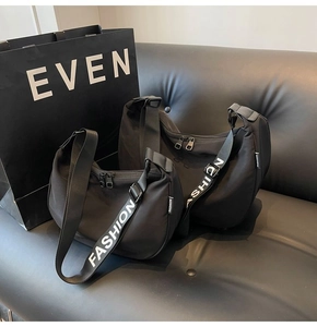 Close-up of waterproof Oxford dumpling bag with 'FASHION' strap on black leather