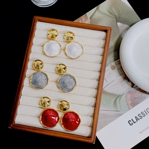 Three pairs of irregular enamel stud earrings in white, grey and red on a velvet tray