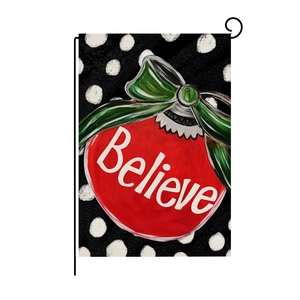 Christmas garden flag with Believe text and red ornament on black polka dot linen background