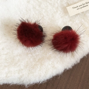 Vue détaillée de boucles d'oreilles pompon rouge foncé sur laine blanche et bois