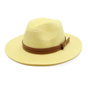 Détail d'un chapeau de paille jaune avec ruban en cuir marron et rivets dorés polis