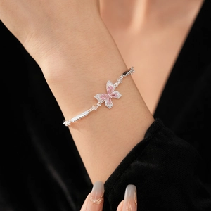 Gros plan d'un élégant bracelet en argent avec pendentif papillon en zircon rose sur un poignet