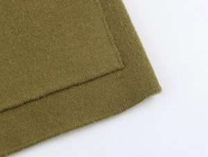 Vista macro della trama in maglia verde oliva e della qualità delle cuciture sull'orlo