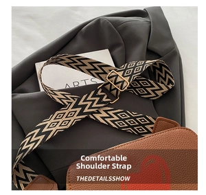Close-up of wide woven shoulder strap with geometric patterns and golden metal buckle