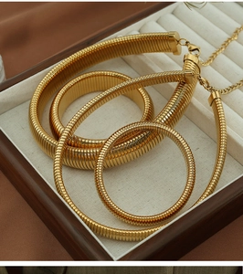 Detailed top view of gold coiled snake bone jewelry set in a luxury wooden box