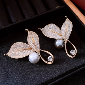 Dettaglio di spillette a foglia placcate oro 18K con zirconi e perle luccicanti