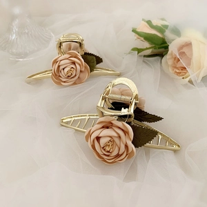 Detailed view of golden flower hair claw clips with pink fabric roses on white tulle