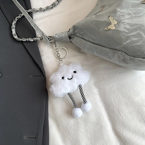 Creative white fluffy cloud bag charm with striped legs hanging on a gray handbag