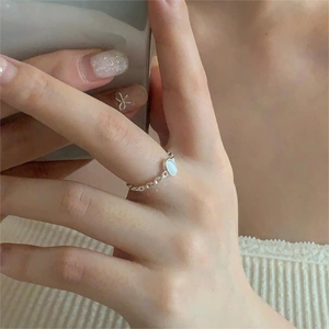 Close-up of minimalist S925 silver chain ring with white oval stone on a finger