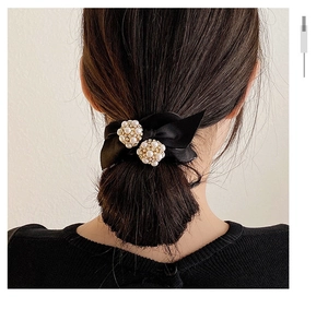 Détail d'un chouchou en soie noire avec perles incrustées sur une coiffure de mannequin
