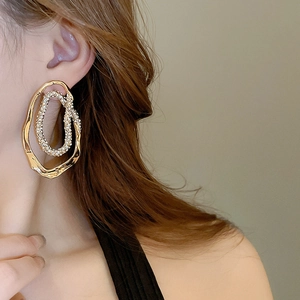 Detail of oversized irregular gold hoop earring with pavé rhinestones on model