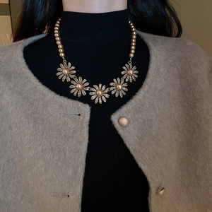 Close-up of vintage golden necklace featuring floral charms and beaded court style design
