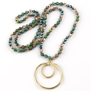 Detailed close-up of beaded necklace with green marble beads and gold double ring pendant