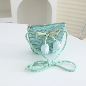 Detail of mint green woven straw bag with tulip pendants and ribbon bow for kids