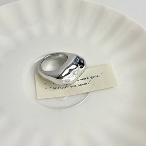 Macro view of minimalist irregular liquid metal alloy ring on white ceramic tray