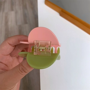 Detailed view of the pink and green color-block heart claw clip and metal spring