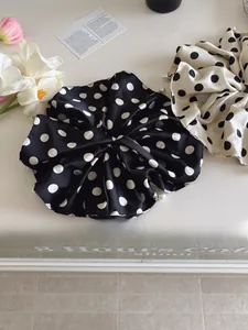 Detailed view of large polka dot satin scrunchies with elegant white pearl embellishments