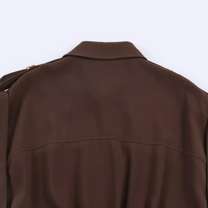 Detailansicht eines dunkelbraunen Midikleids mit Schulterriemen und Metallring-Details