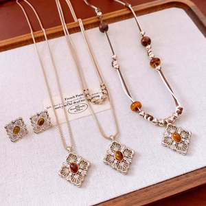 Detailed set of tiger eye hollow flower necklaces and earrings on a wooden jewelry tray