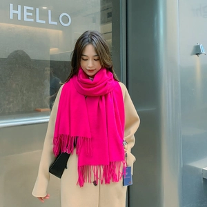Detail of rose red cashmere scarf with tassels styled on a model in beige coat