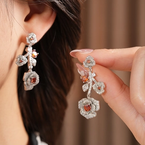Detailed view of vintage rose earrings with orange stones and zircon insets on model