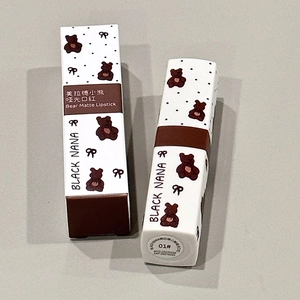 Matte bear lipstick in shade 01 with packaging box on a grey surface detail view