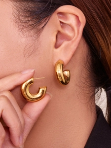 Detailed side view of thick chunky golden C-hoop earrings worn by a fashion model